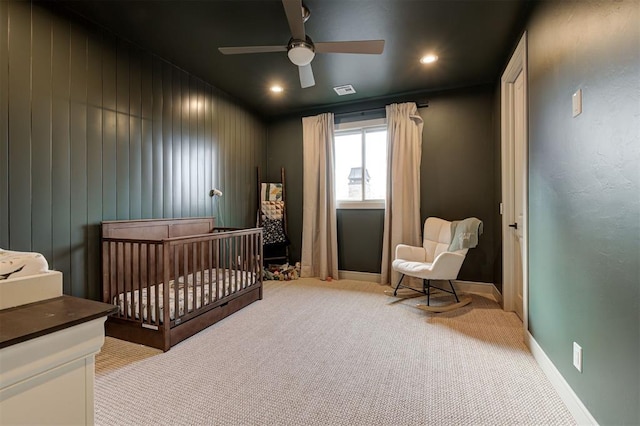 bedroom with light carpet, ceiling fan, and a crib