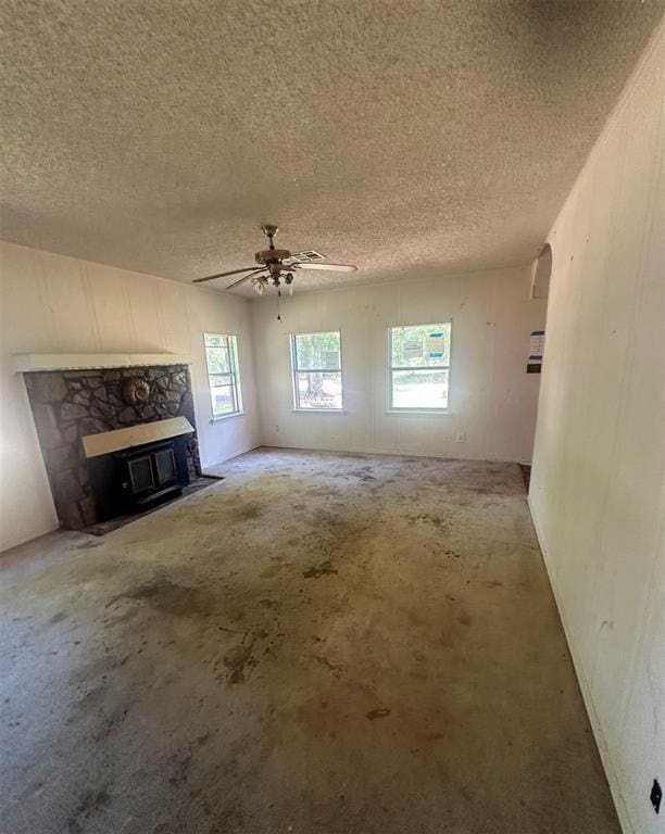 unfurnished living room with a fireplace, a textured ceiling, and ceiling fan