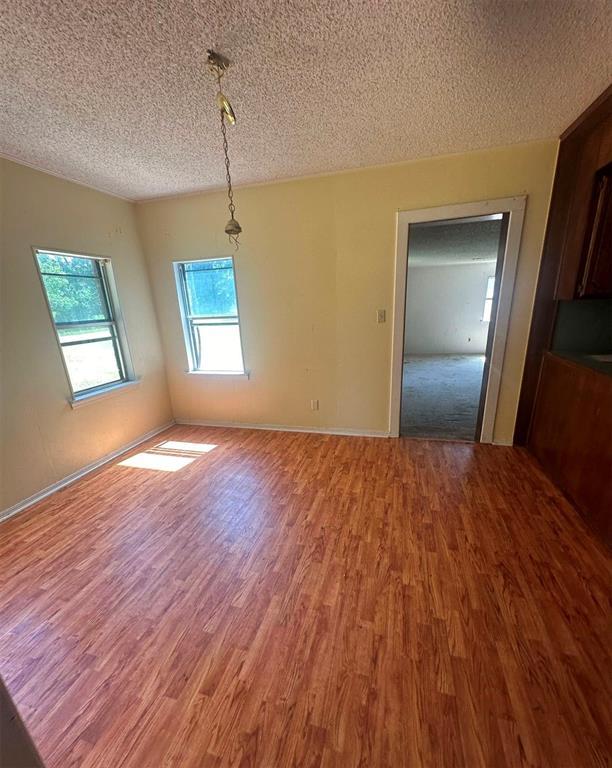 unfurnished dining area with wood-type flooring and a textured ceiling