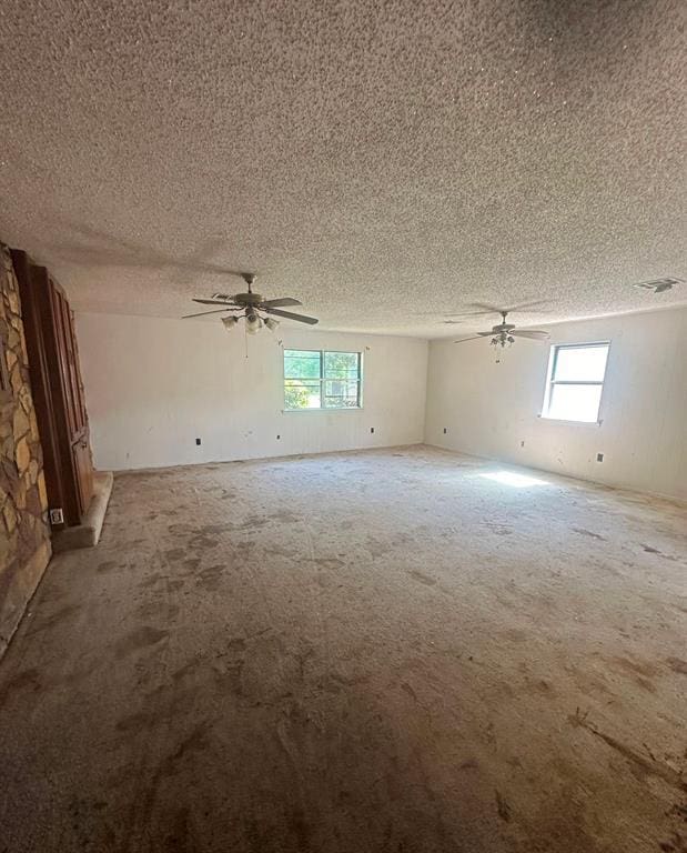 unfurnished room featuring plenty of natural light, a textured ceiling, and ceiling fan