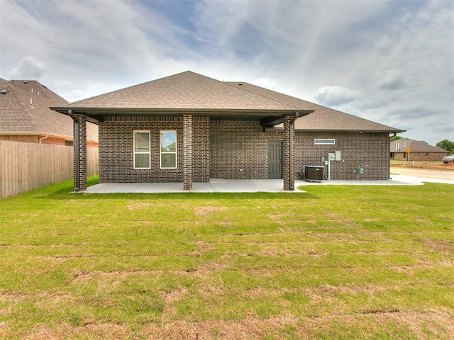 rear view of property featuring brick siding, a yard, a shingled roof, a patio area, and fence