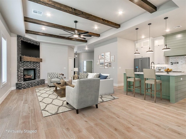 living room featuring visible vents, a brick fireplace, ceiling fan, light wood-type flooring, and baseboards