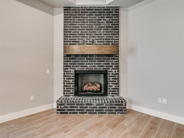 interior details with a fireplace, baseboards, and wood finish floors