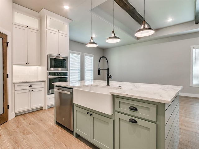 kitchen with stainless steel appliances, green cabinetry, a sink, and light wood finished floors