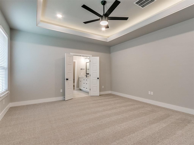 unfurnished room featuring a raised ceiling, visible vents, and baseboards