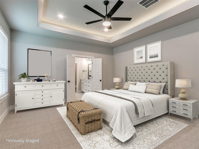 bedroom featuring baseboards, visible vents, a raised ceiling, and light colored carpet