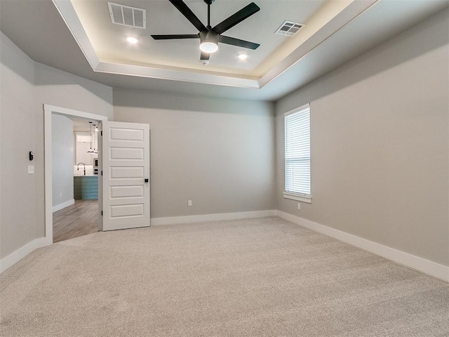 carpeted spare room featuring baseboards, visible vents, and a raised ceiling