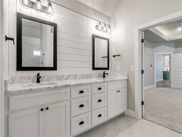 bathroom with double vanity, baseboards, visible vents, and a sink