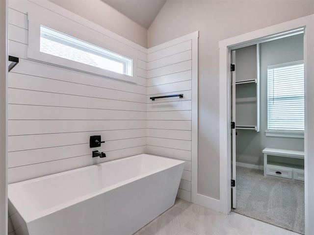 full bath featuring vaulted ceiling, a freestanding tub, and a walk in closet