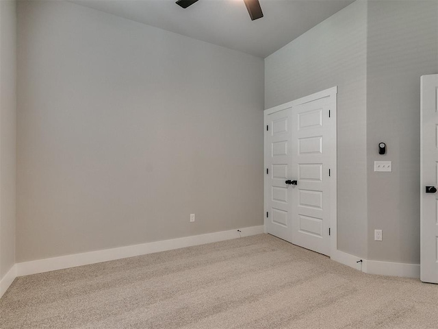 carpeted empty room featuring ceiling fan and baseboards