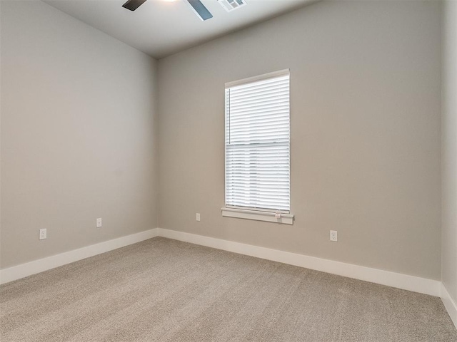 carpeted spare room featuring ceiling fan, visible vents, and baseboards