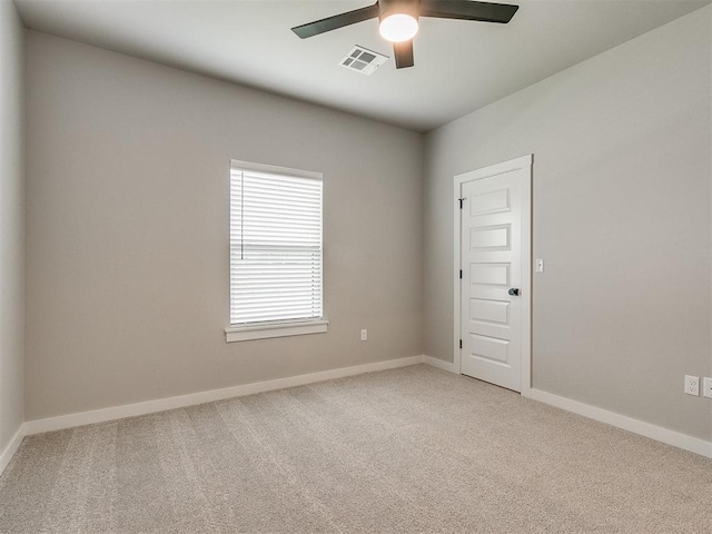 spare room featuring light carpet, ceiling fan, visible vents, and baseboards