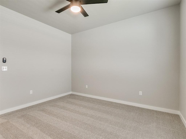 carpeted empty room with a ceiling fan and baseboards