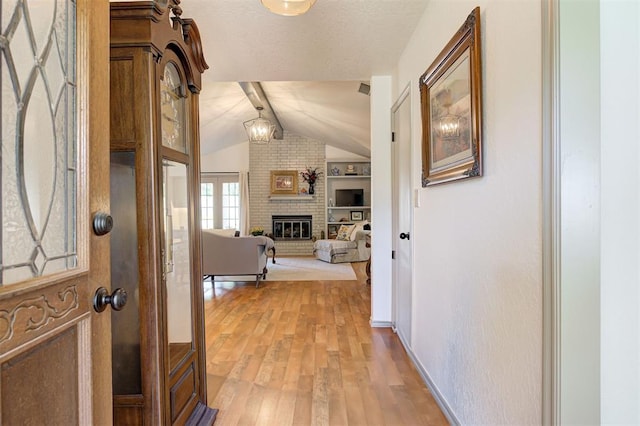 hallway featuring light wood-type flooring, lofted ceiling with beams, and built in features