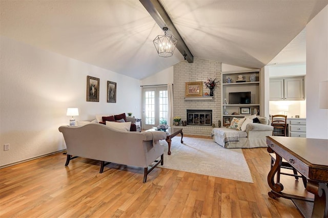 living room with a brick fireplace, vaulted ceiling with beams, an inviting chandelier, light hardwood / wood-style flooring, and built in features