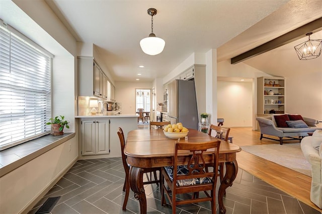 dining space with lofted ceiling with beams and a notable chandelier