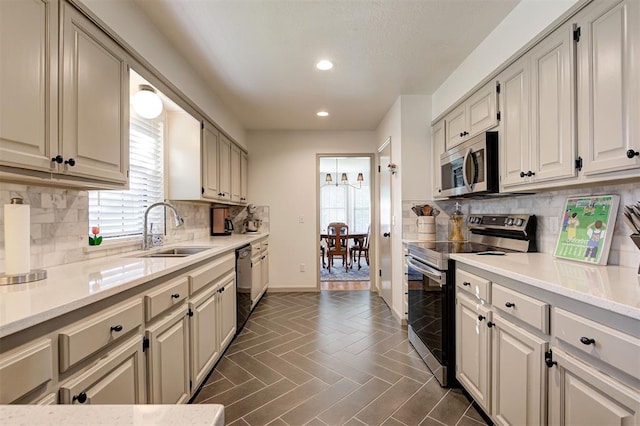 kitchen featuring dark tile patterned floors, stainless steel appliances, decorative backsplash, sink, and light stone counters