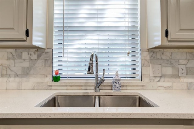 kitchen featuring light stone countertops, sink, and backsplash