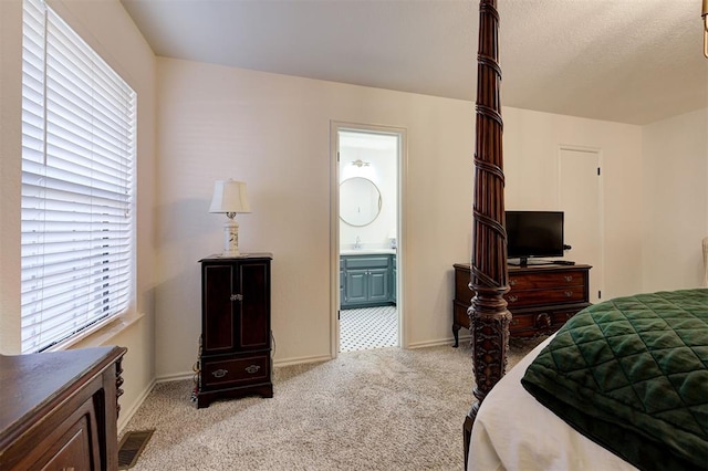 bedroom with sink, ensuite bathroom, and light carpet