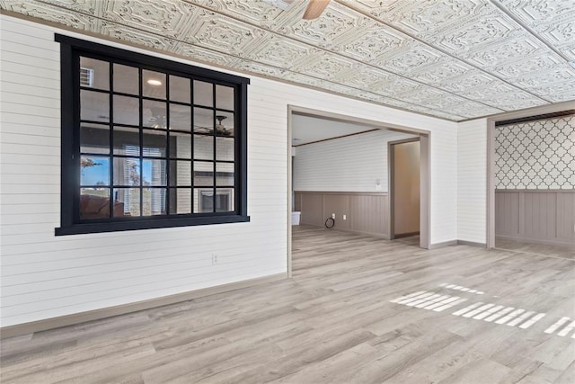 unfurnished living room featuring light hardwood / wood-style flooring and wooden walls