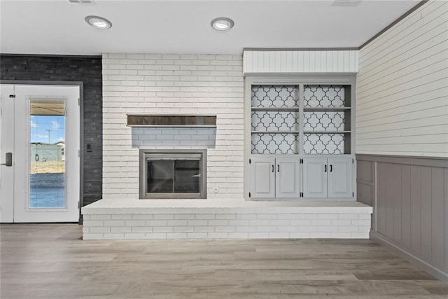 unfurnished living room featuring hardwood / wood-style flooring, built in shelves, and wooden walls