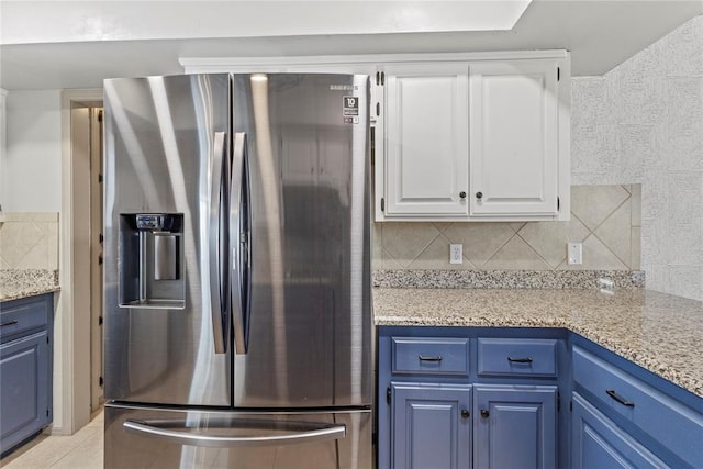 kitchen featuring white cabinets, stainless steel fridge, blue cabinetry, and tasteful backsplash