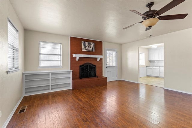 unfurnished living room with ceiling fan, a brick fireplace, and hardwood / wood-style floors