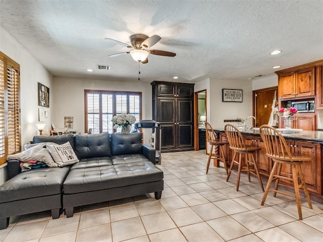 tiled living room with ceiling fan and a textured ceiling