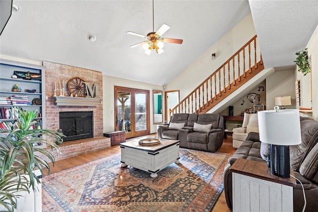 living room featuring a brick fireplace, lofted ceiling, a textured ceiling, and light hardwood / wood-style flooring