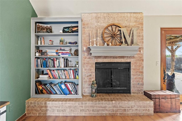 sitting room featuring hardwood / wood-style flooring, a fireplace, and built in shelves