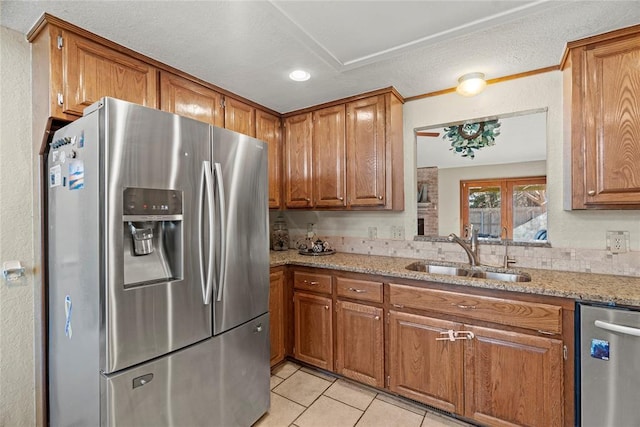 kitchen featuring light stone counters, appliances with stainless steel finishes, light tile patterned flooring, and sink