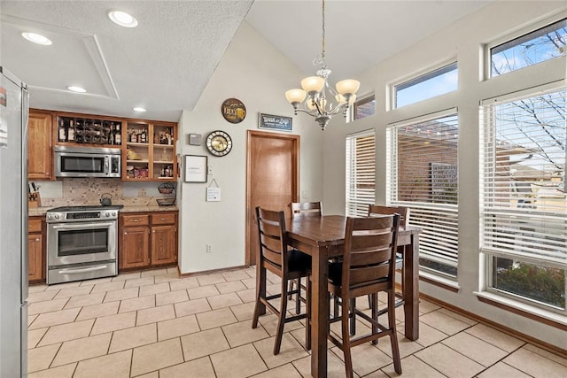 tiled dining room with lofted ceiling, a textured ceiling, and a chandelier