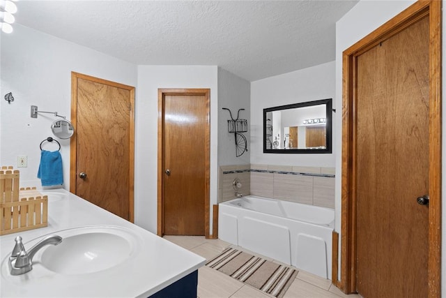 bathroom featuring tile patterned floors, vanity, a bathtub, and a textured ceiling