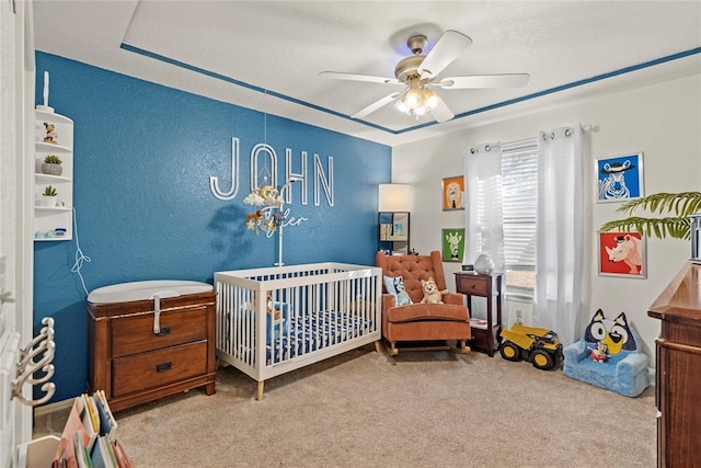 bedroom with light colored carpet, a nursery area, and ceiling fan