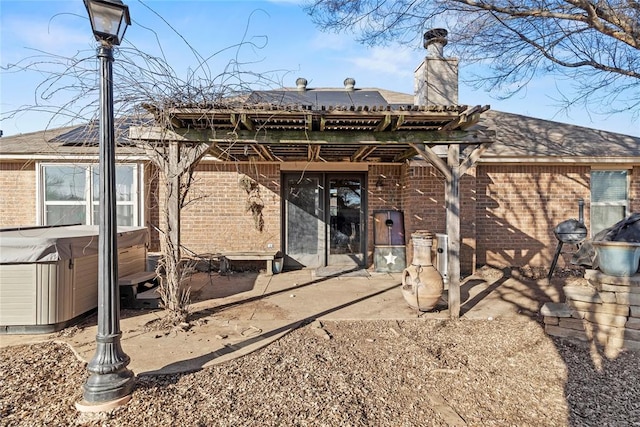 rear view of house with a hot tub and a patio area