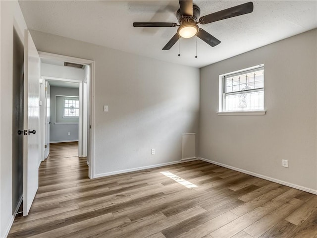 empty room with ceiling fan and light hardwood / wood-style floors