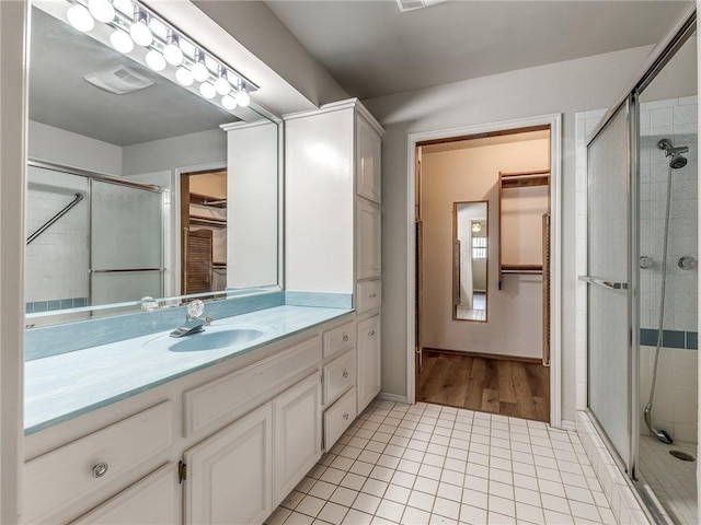 bathroom with a shower with door, vanity, and tile patterned flooring