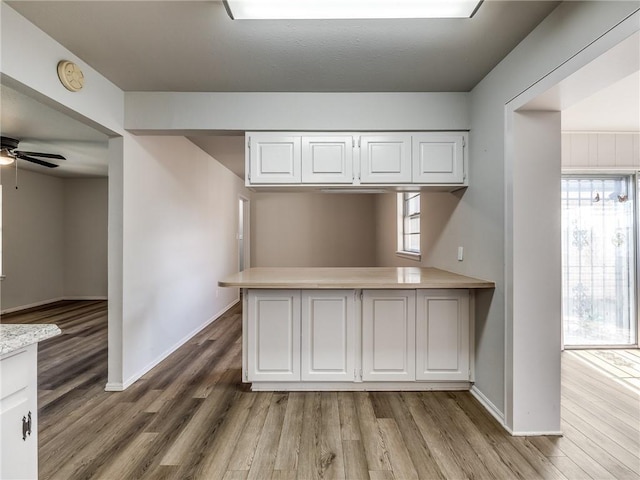 kitchen with ceiling fan, kitchen peninsula, white cabinetry, and light hardwood / wood-style flooring