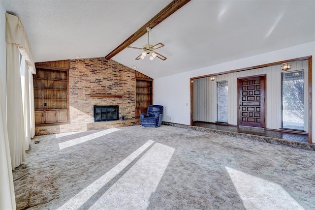 unfurnished living room featuring vaulted ceiling with beams, carpet, ceiling fan, a brick fireplace, and built in shelves