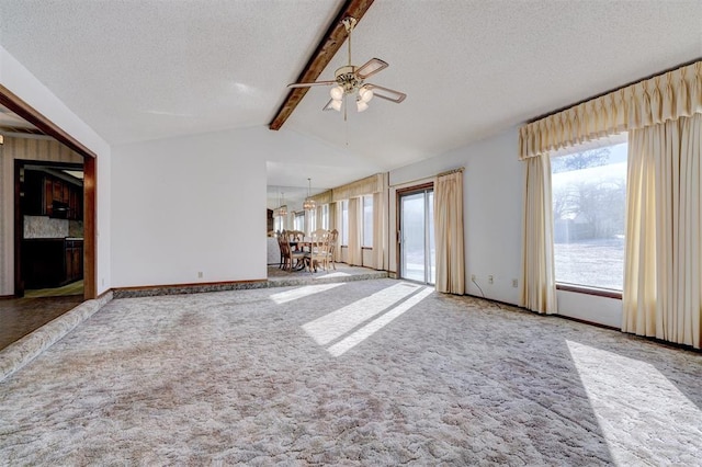 unfurnished living room featuring vaulted ceiling with beams, plenty of natural light, and a textured ceiling