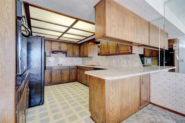 kitchen featuring sink, kitchen peninsula, and black fridge