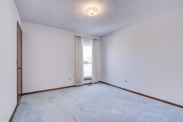 unfurnished room featuring light carpet and a textured ceiling