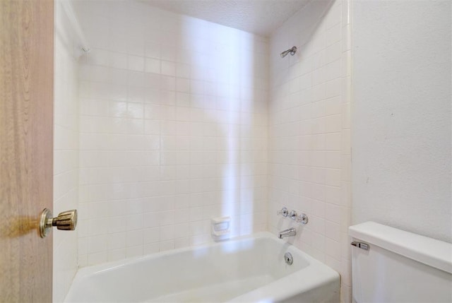 bathroom with bathtub / shower combination, toilet, and a textured ceiling