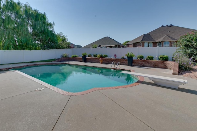 view of swimming pool with a diving board and a patio