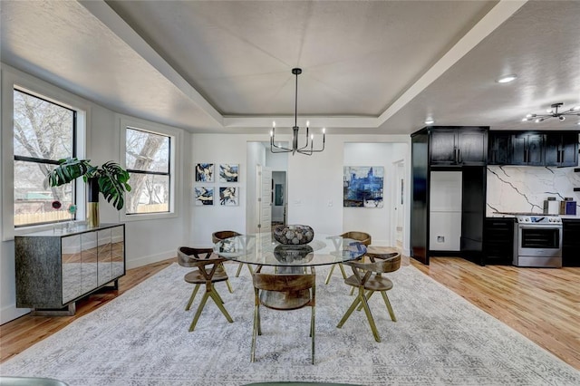 dining room featuring a raised ceiling, wood-type flooring, and a notable chandelier