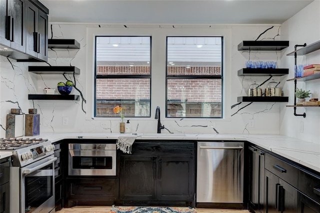 kitchen featuring light stone counters, sink, stainless steel appliances, and tasteful backsplash