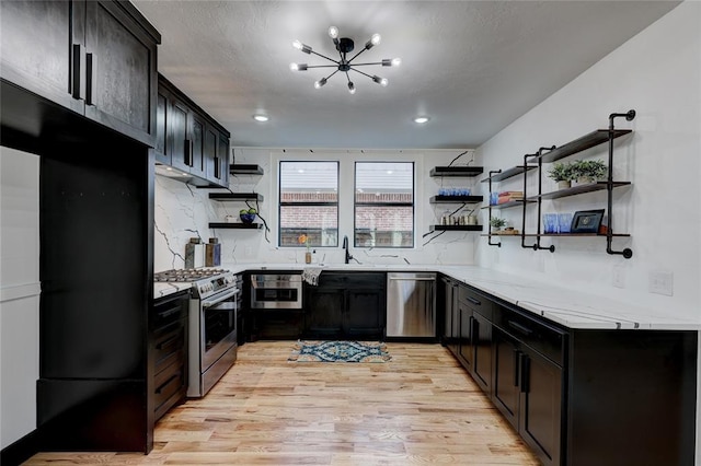 kitchen featuring decorative backsplash, appliances with stainless steel finishes, light stone counters, and light hardwood / wood-style floors