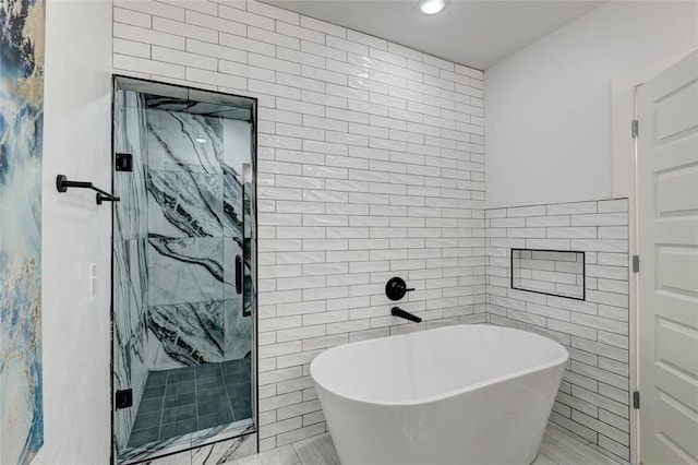 bathroom featuring tile walls and separate shower and tub