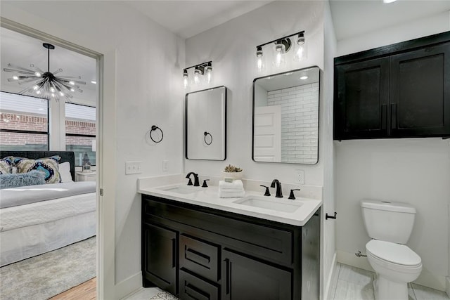 bathroom featuring wood-type flooring, toilet, vanity, and an inviting chandelier