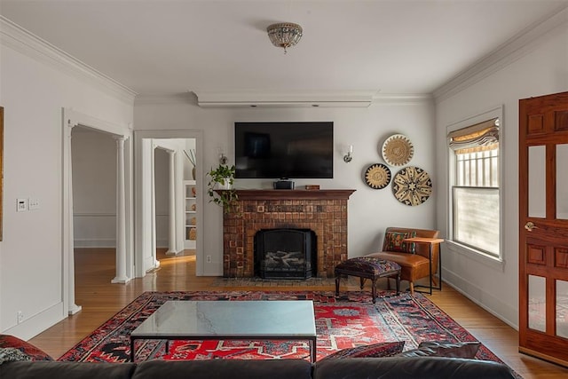 living room with ornamental molding, a fireplace, and hardwood / wood-style floors